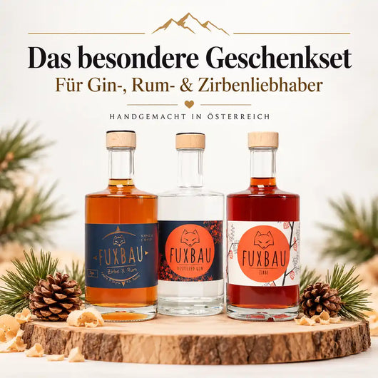 FUXBAU Geschenkset mit handgemachtem Gin, Zirbe x Rum und Zirbenlikör aus Österreich. Drei edle Spirituosenflaschen auf einer Holzscheibe mit Tannenzapfen, ideal als Geschenk für Gin-, Rum- und Zirbenliebhaber.