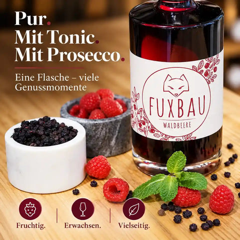 FUXBAU Waldbeere Gin-Likör mit Glas und Himbeeren – fruchtig pur, mit Tonic oder Prosecco genießen.
